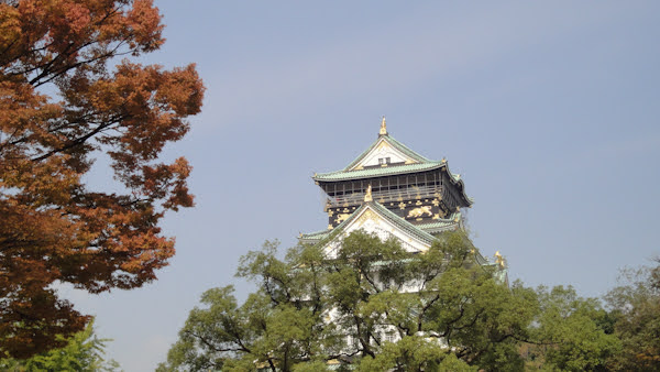 the top of the castle towers over trees in the foreground